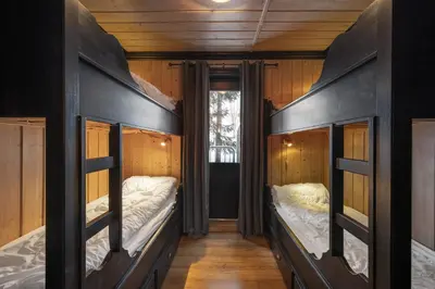 two beds in a room with wooden walls at Tinden Apartments in Hemsedal