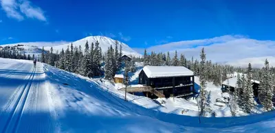 a building in the snow with a mountain in the background at Gausta View in Gaustablikk