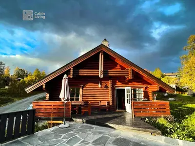 a log cabin with a umbrella on a deck at Cozy cottage in central Beitostølen with Sauna in Beitostøl