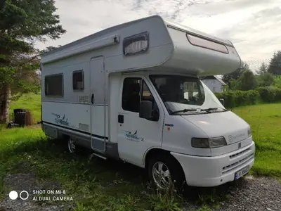 a white camper truck parked in a field at Airbnb and Booking at Postvegen 95 in Vigra