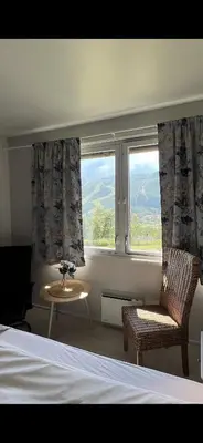 a bedroom with a bed and a chair and a window at Hallingskarvet Fjellstue as in Hovet
