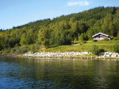 a house on a hill next to a body of water at 6 person holiday home in VATNE-By Traum in Vatne