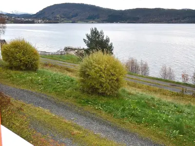 a road next to a body of water with bushes at 6 person holiday home in VATNE-By Traum in Vatne