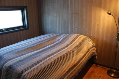 a bed in a corner of a room with a window at Skarvhytta - moderne hytte med flott beliggenhet in Hol