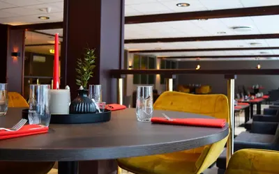 a table in a restaurant with glasses and chairs at Rjukan Hotell in Rjukan