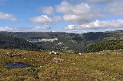 a view of a grassy field with mountains in the background at Kråkehaugen Feriehus, a perfect holiday retreat near Åheim in Åheim