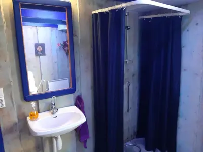 a bathroom with a sink and a shower with a blue shower curtain at Kvamshaugen hytter in Luster