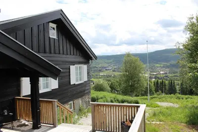a black house with a wooden porch and a balcony at Solsiden - in the center of Geilo in Geilo