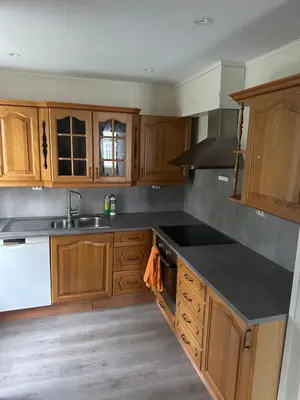 a kitchen with wooden cabinets and a black counter top at Downtown Historical House with Renovated apartments free P near in Ålesund
