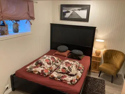 a bedroom with a bed with red sheets and a chair at Downtown Historical House with Renovated apartments free P near in Ålesund