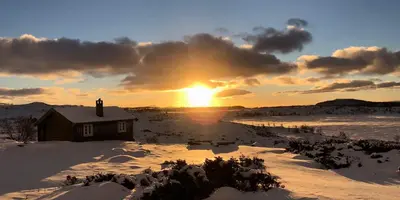 a house in the snow with the sunset in the background at Olebu in Skammestein