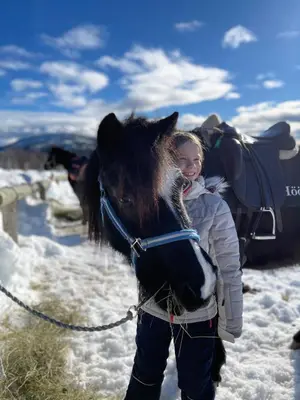 a young girl holding a horse on a snow covered slope at Hytte på Myhre Gård in Skammestein
