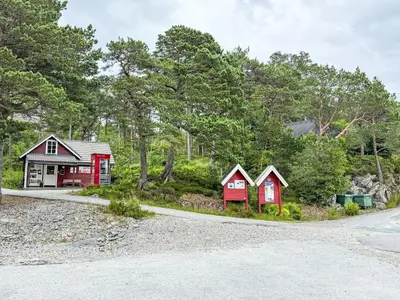 a house with three red houses next to a road at Chalet Svanöy by Interhome in Grimeli