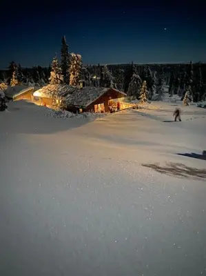 a log cabin in the snow with a person skiing at Hytte sentralt Ljøsheim, Ringsaker(nær Sjusjøen) in Ringsaker