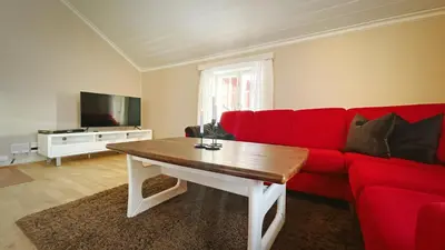 a living room with a red couch and a table at Finnegården Røros in Røros