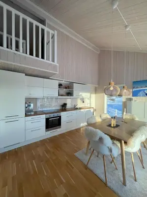 a kitchen with white cabinets and a wooden table and chairs at Skarvebo - cabin with amazing view in Hol