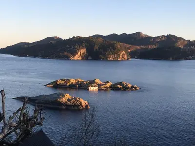 a group of rocks in a large body of water at Bergen/Sotra: Sea cabin. Spa. Fishing. Boat in Haganes