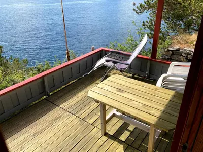 a wooden deck with a bench and a table on it at Bergen/Sotra:Waterfront cabin(s).Boat.Fish.Jacuzzi in Haganes