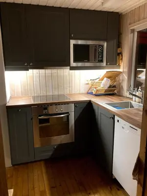 a kitchen with black cabinets and a microwave at Bergen/Sotra:Waterfront cabin(s).Boat.Fish.Jacuzzi in Haganes