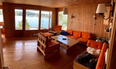 a living room with orange furniture and a large window at Bergen/Sotra:Waterfront cabin(s).Boat.Fish.Jacuzzi in Haganes