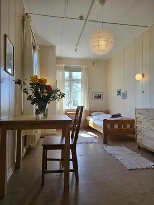 a room with a table and a bedroom with a bed at Fokhol Gård Gjestehus in Stange