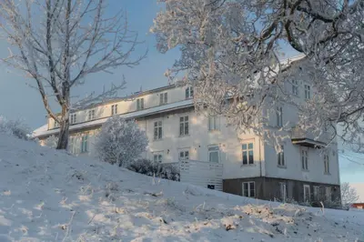 a building on a hill with snow on the ground at Fokhol Gård Gjestehus in Stange