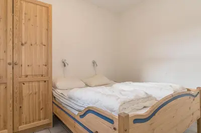 a bed in a room with a wooden cabinet at Skitorget Apartments in Trysil
