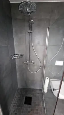 a bathroom with a shower with a sink and a toilet at Lovely 2-bedroom loft with panoramic view. in Kristiansund
