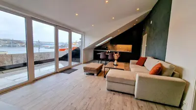 a living room with a couch and a large window at Lovely 2-bedroom loft with panoramic view. in Kristiansund
