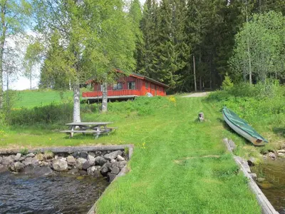 a red cabin with a table and a canoe in the grass at Festly in Ringsaker