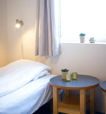 a bedroom with a bed and a table and a window at Sjøholt Sommerhotell in Ørskog