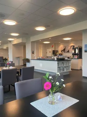 a cafeteria with a table with a vase of flowers on it at Sjøholt Sommerhotell in Ørskog