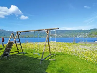 a swing set in a field next to a body of water at 6 person holiday home in TYSSE-By Traum in Tysse