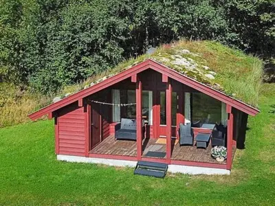 a red building with a grassy roof with chairs and a deck at 6 person holiday home in olden in Olden