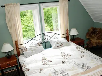 a bedroom with a bed with a white comforter and two windows at 6 person holiday home in LONEVÅG-By Traum in Lonevåg