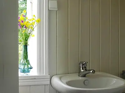 a bathroom sink with a vase of flowers in a window at 6 person holiday home in LONEVÅG-By Traum in Lonevåg