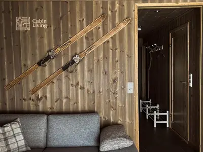 a hockey stick on a wooden wall with a couch at Modern ski-in out apartment at Sjusjøen in Sjusjøen