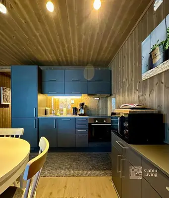 a kitchen with blue cabinets and a table at Modern ski-in out apartment at Sjusjøen in Sjusjøen