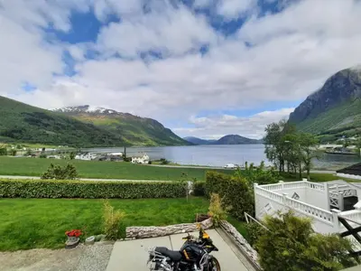 a motorcycle parked on a patio next to a body of water at Fjordgaestehaus in Innfjorden
