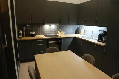 a kitchen with black cabinets and a table with chairs at Beautiful penthouse with panoramic view at Sjusjøen in Ringsaker