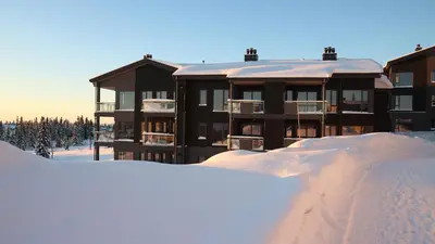 a building in the snow with a pile of snow at Beautiful penthouse with panoramic view at Sjusjøen in Ringsaker