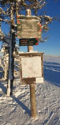 a sign in the snow next to a tree at Beautiful penthouse with panoramic view at Sjusjøen in Ringsaker