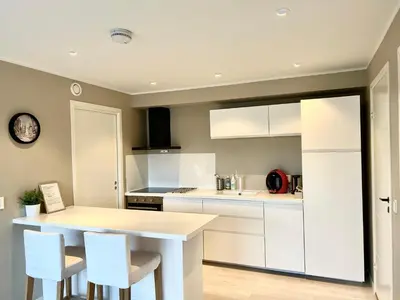 a kitchen with white cabinets and a table and chairs at Havn i Etne with fjordview in Etnesjøen