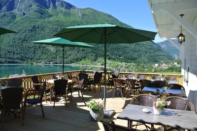 a patio with tables and chairs with a view of a mountain at Eide Gardshotell in Skjolden