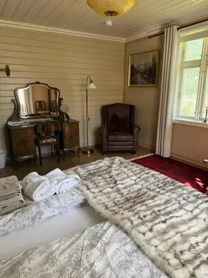 a bedroom with a bed with towels and a chair at Eide Gardshotell in Skjolden