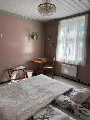 a bedroom with a bed and a table and a chandelier at Eide Gardshotell in Skjolden