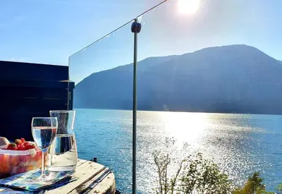 a table with two glasses and a bowl of fruit next to the water at Mikrohyttene i Åkrafjorden in Etnesjøen