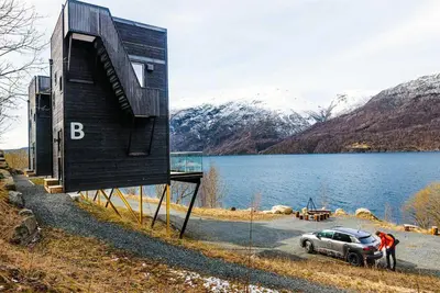 a small house with a car parked next to a body of water at Mikrohyttene i Åkrafjorden in Etnesjøen