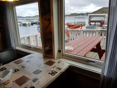 a balcony with a table and a view of a boat at Havgløtt in Oksvoll