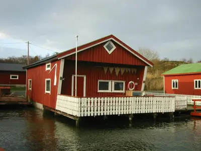 a red house on a dock in the water at Havgløtt in Oksvoll